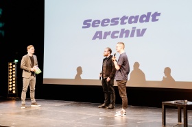 Moderator Felix Krömer (l.) im Gespräch mit Jan Braetsch und Niklas Piatkovski (v.l.) von SEESTADT ARCHIV