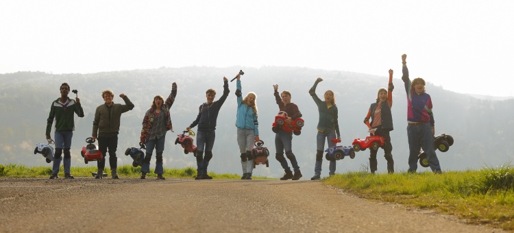 Die REAL LIFE GUYS mit Bobby Cars (v.l.): Serge Mateso (Max), Laurenz Lerch (Louis), Janina Fautz (Ava), Anton Fuchs (Johannes Mickenbecker), Kya-Celina Barucki (Elli Mickenbecker), Richard Fuchs (Philipp Mickenbecker), Samirah Breuer (Nele), Amelie Willberg (Luca) und Michael Schweisser (Carlo) © Tom Trambow / Paramout Pictures Germany