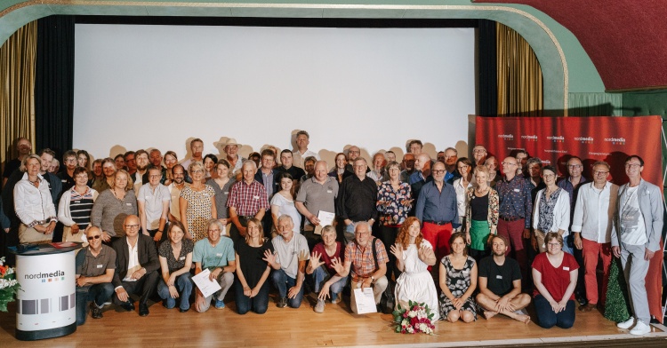 Ausgezeichnetes Kino: die Kinoprogrammpreisträger und -preisträgerinnen 2019 mit Preispatin Marleen Lohse (vorne knieend mit Blumenstrauß) auf der Bühne der Gronauer Lichtspiele © nordmedia/David Carreño Hansen