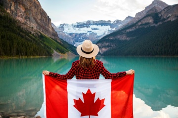 Frau mit Kanada-Flagge vor Seenlandschaft